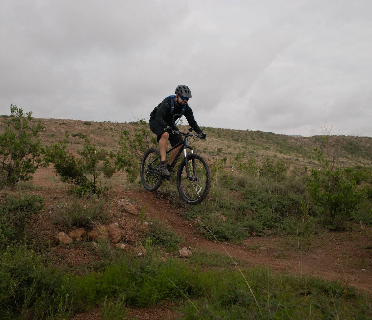 Rider enjoying a scenic mountain ebike ride on a pine-lined forest trail with Cascade Range in background