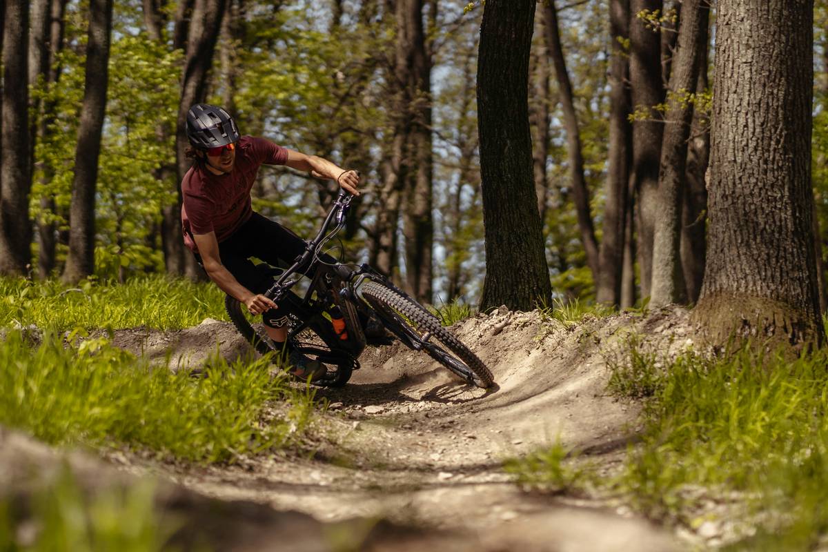 Rider using mountain bike boost on steep forest trail with Deschutes River backdrop